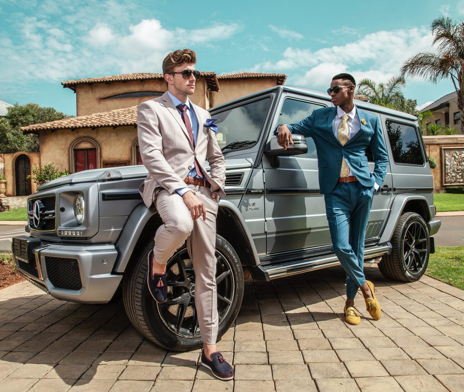 Two men in tailored suits beside a Mercedes-Benz G-Class