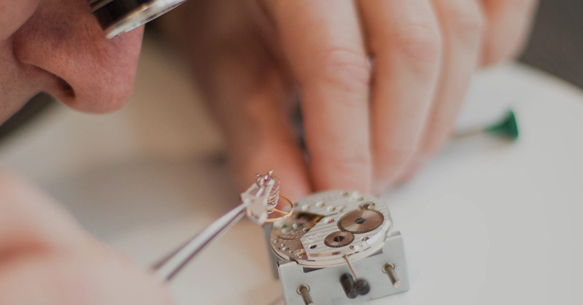 Watchmaker assembling a movement with tweezers