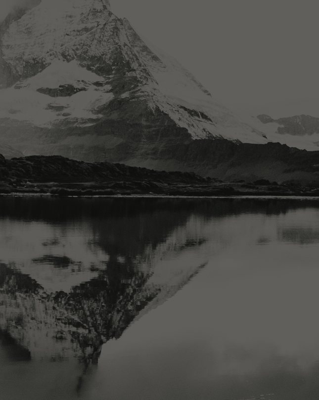 A still alpine lake reflecting the peaks above it